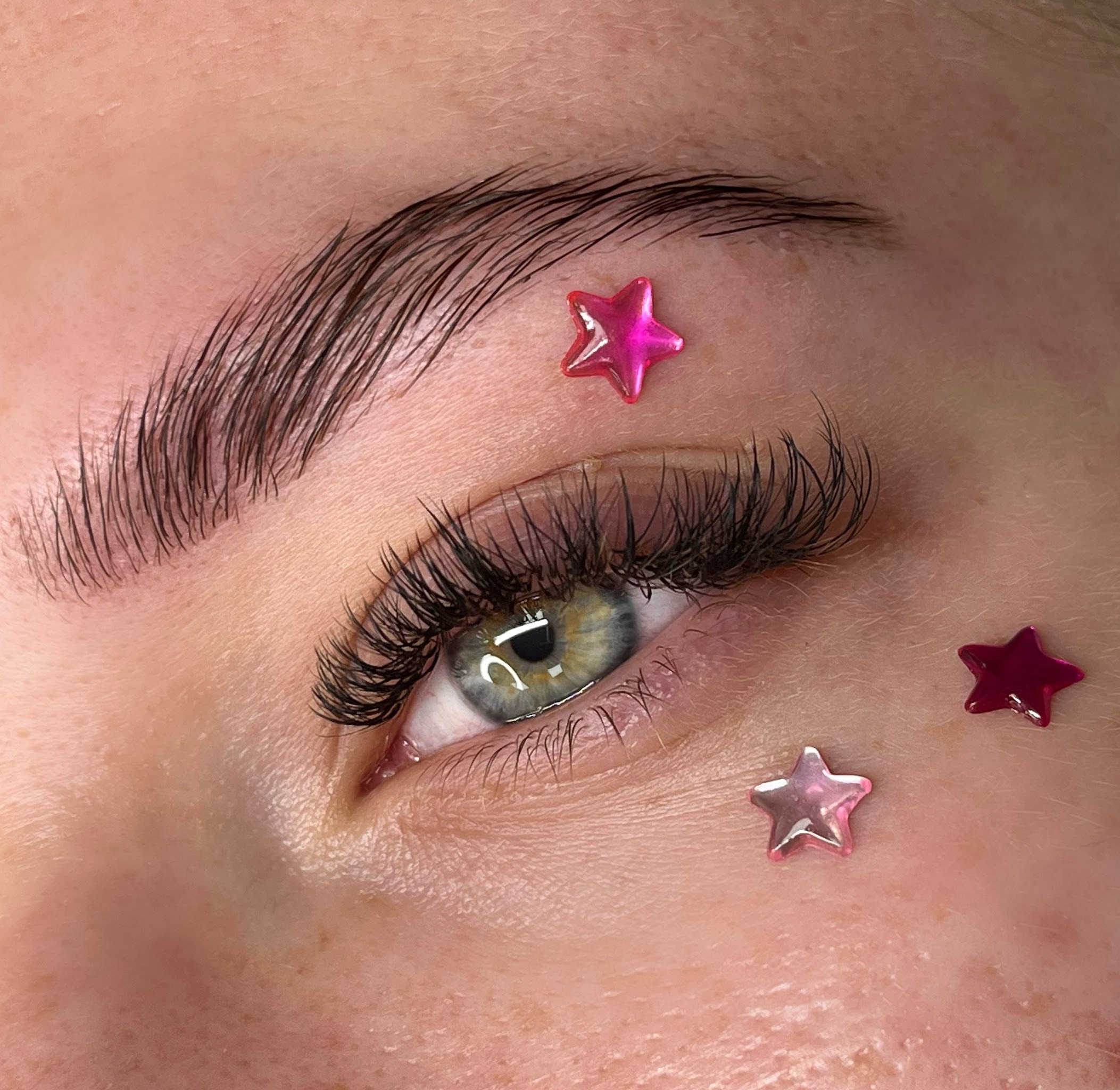 Wimperextensions met roze sterretjes op de wang, een one by one set